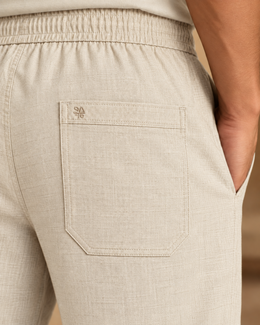 Close-up of beige linen cotton pajama pants back patch pocket with tonal SA embroidery