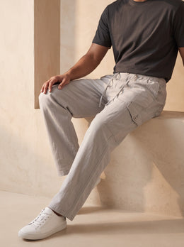 Seated detail view of men’s grey cotton linen cargo pants showing the buttoned thigh cargo pocket